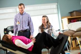 Therapists work with a patient on an incline bench.